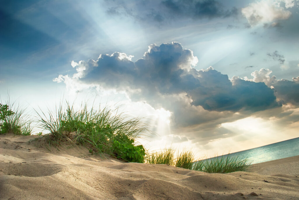 About Lane One Foundation; image of the dunes with sun rays shining through the clouds